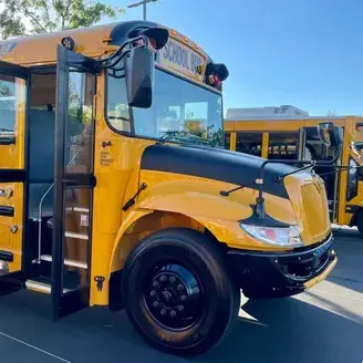 A row of yellow school buses parked in a parking lot.