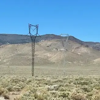 A power pole in the middle of nowhere with mountains behind it.