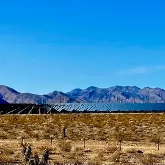 A desert landscape with mountains in the background and solar panels generating clean energy.