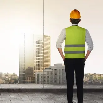 A man in yellow vest and hard hat looking at building.