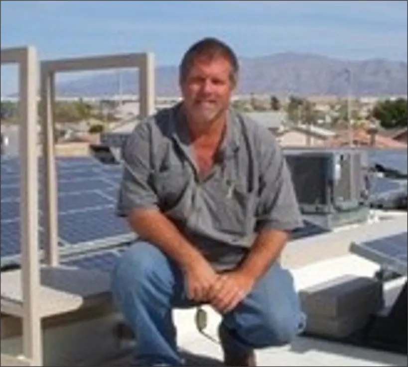 A man sitting on top of a roof with solar panels.