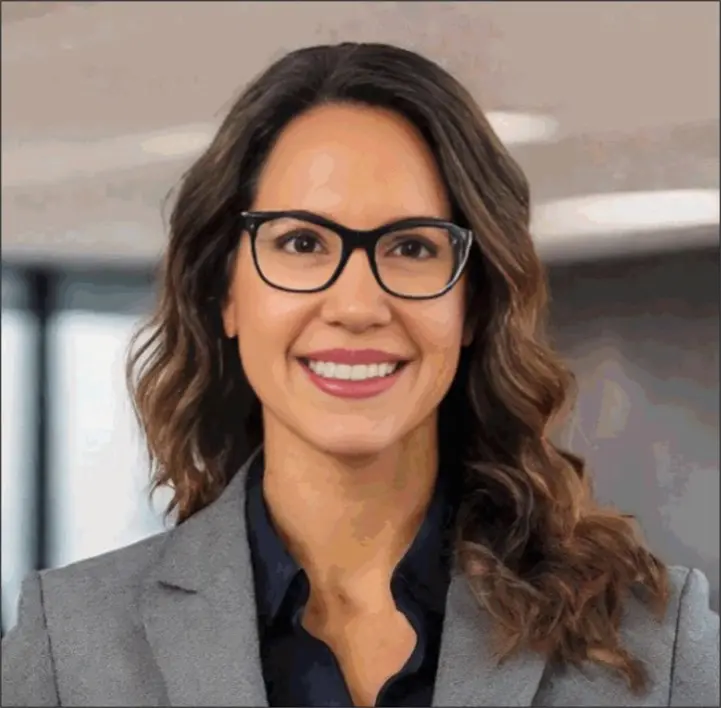 A woman in glasses and a suit smiling for the camera.