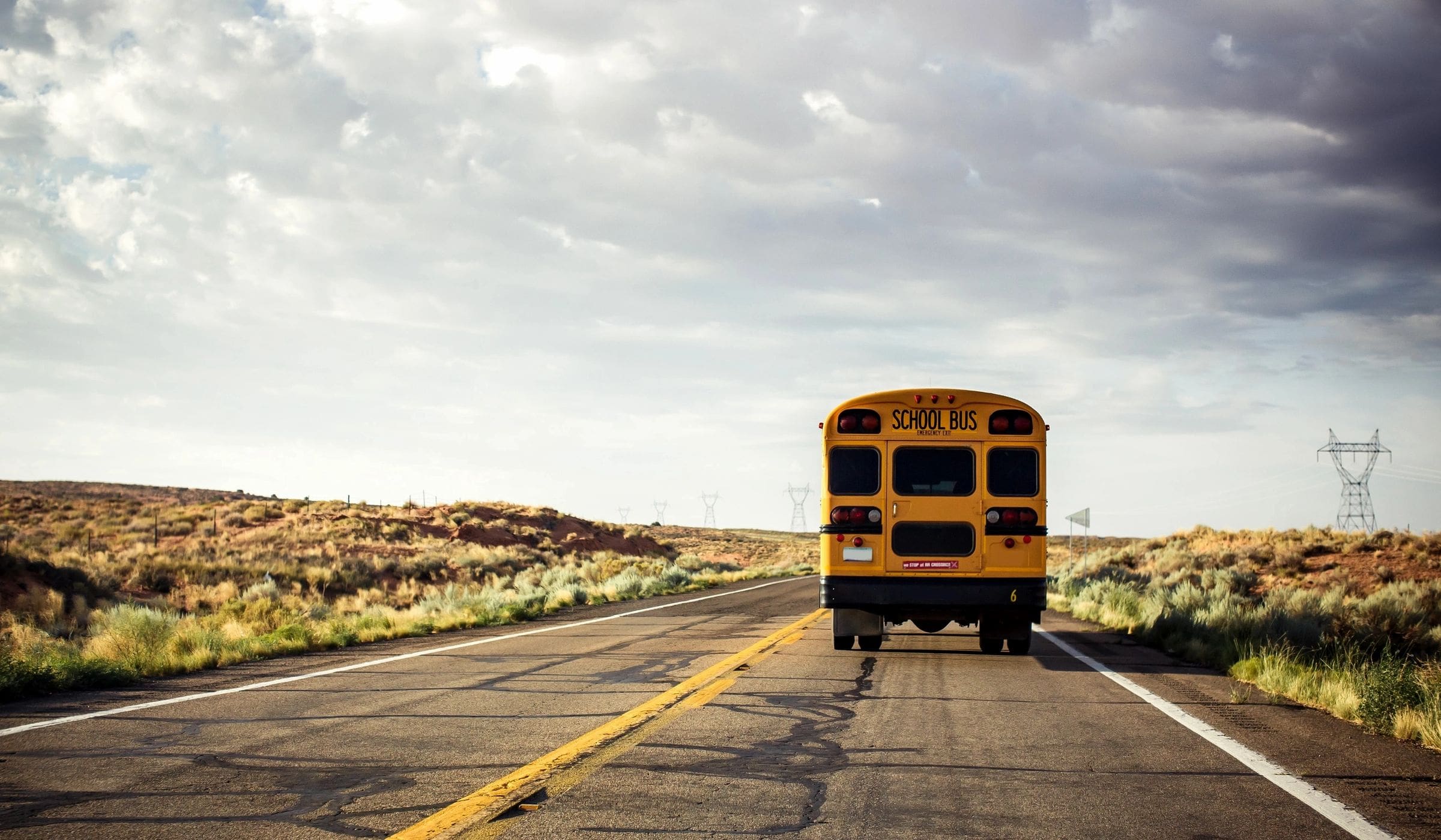 The rear end of a school bus driving on a rural road.