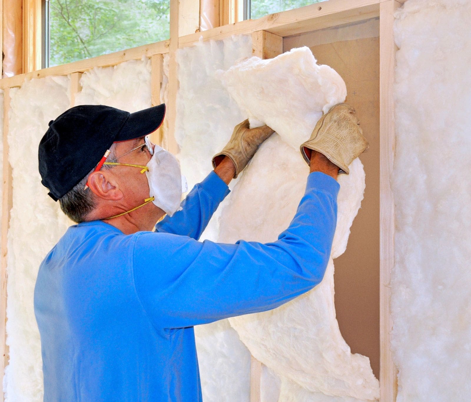 A man installing a layer of energy saving insulation into a wall.