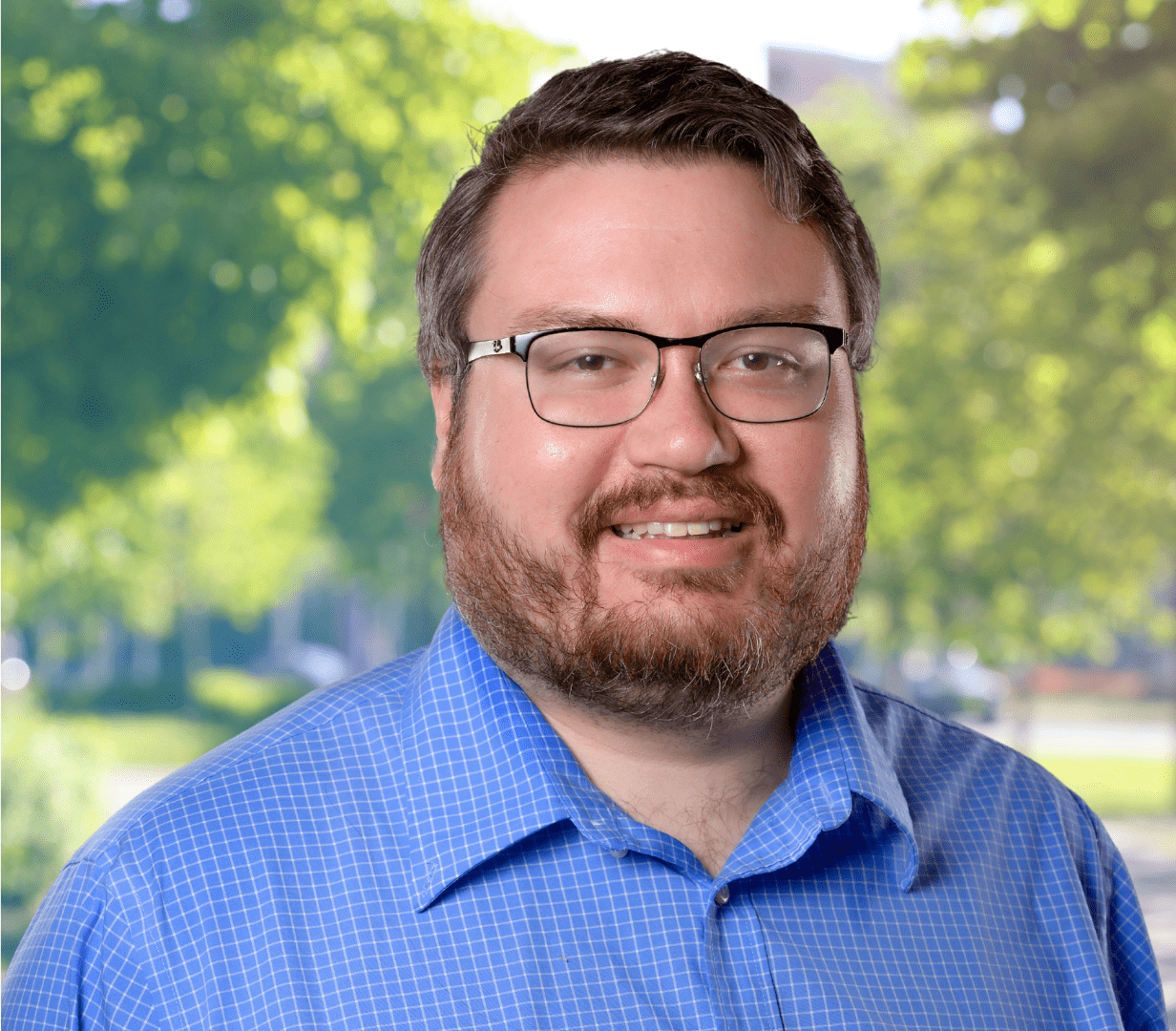 Smiling man wearing glasses and blue shirt.