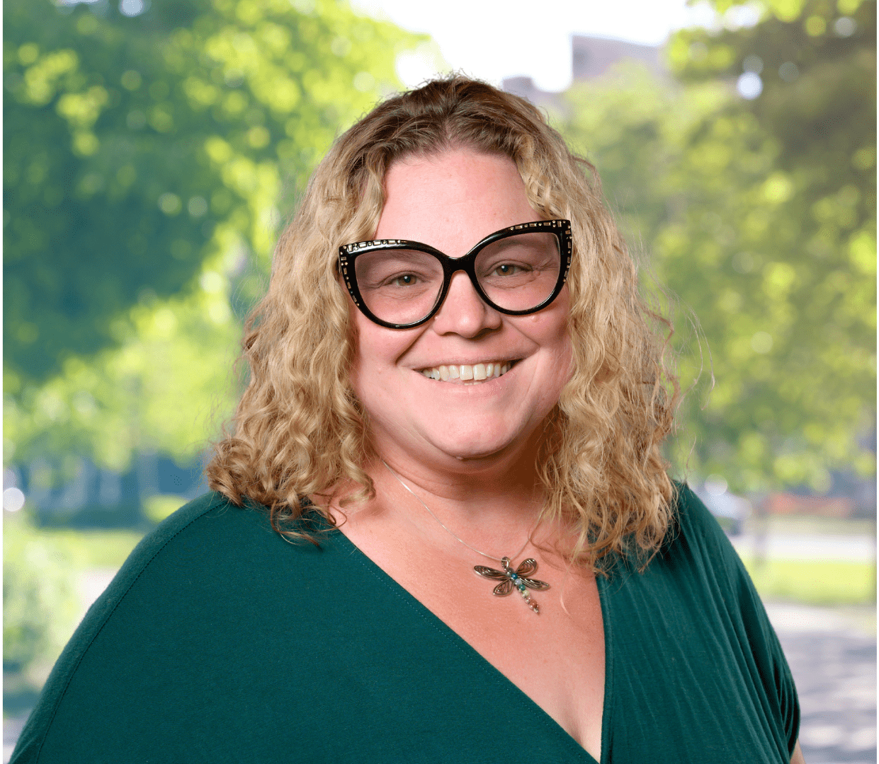 Headshot of woman with glasses and dragonfly necklace.