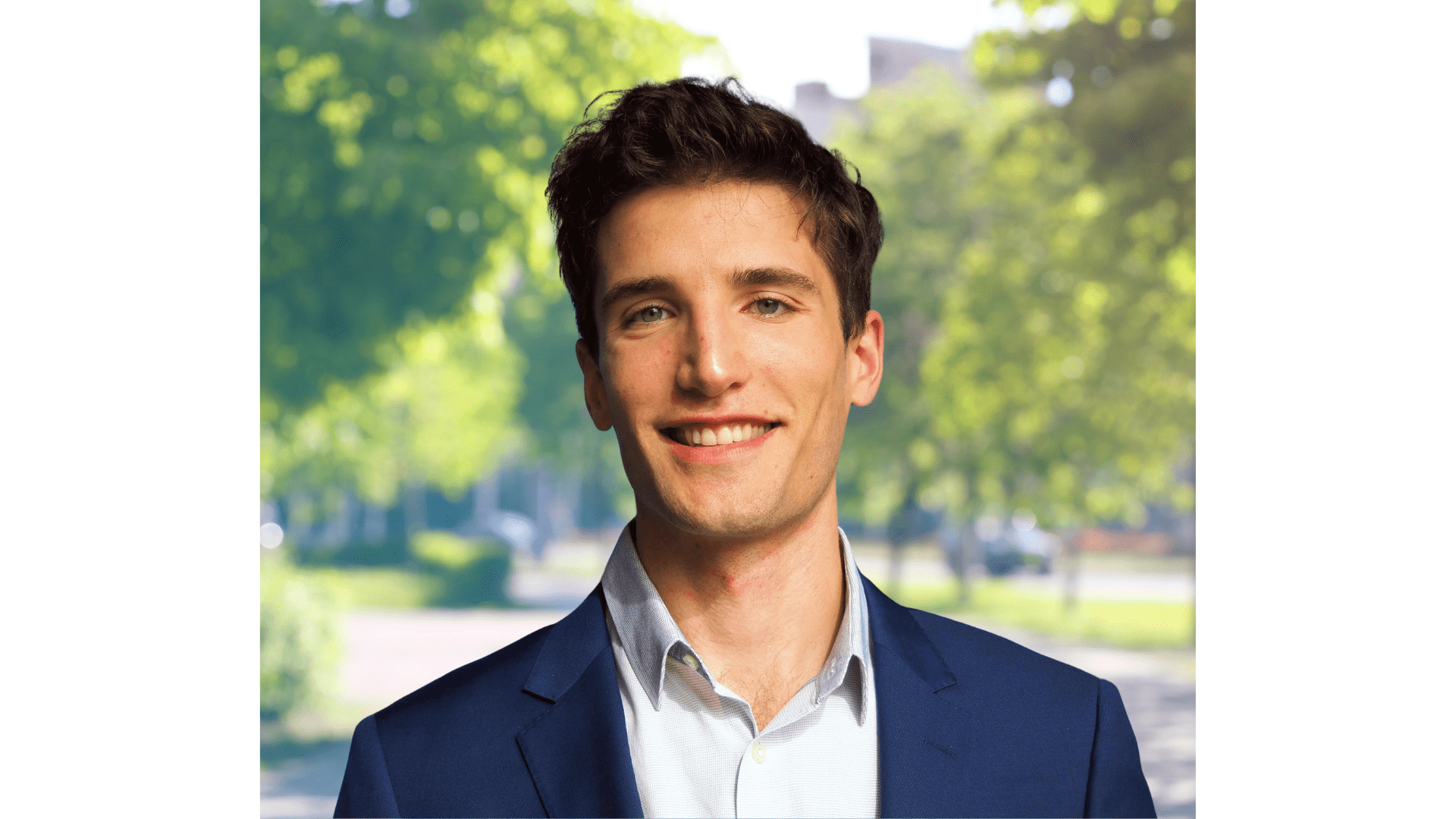 Smiling man in blue suit outdoors.